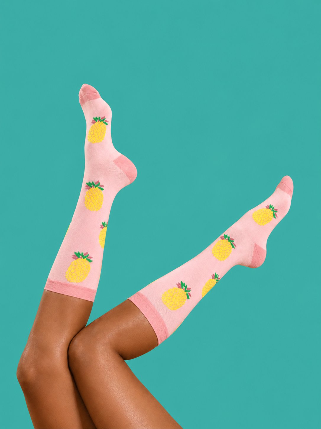 Joyful compression in pink pineapple knee-high socks on a teal background